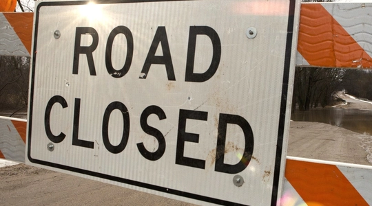 Image of a road closure sign and barricade.