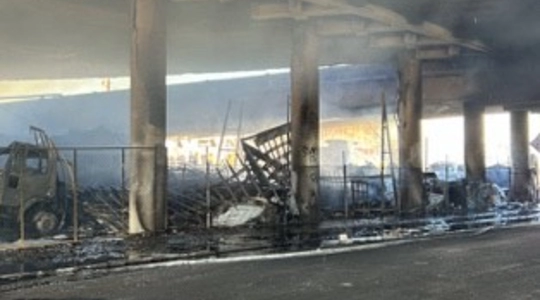 Photo of burned-out area under the Alameda overpass of the 10 Freeway, damagesd by a major pallet fire early Saturday, November 11, 2023. Burned pillars and concrete are seen.