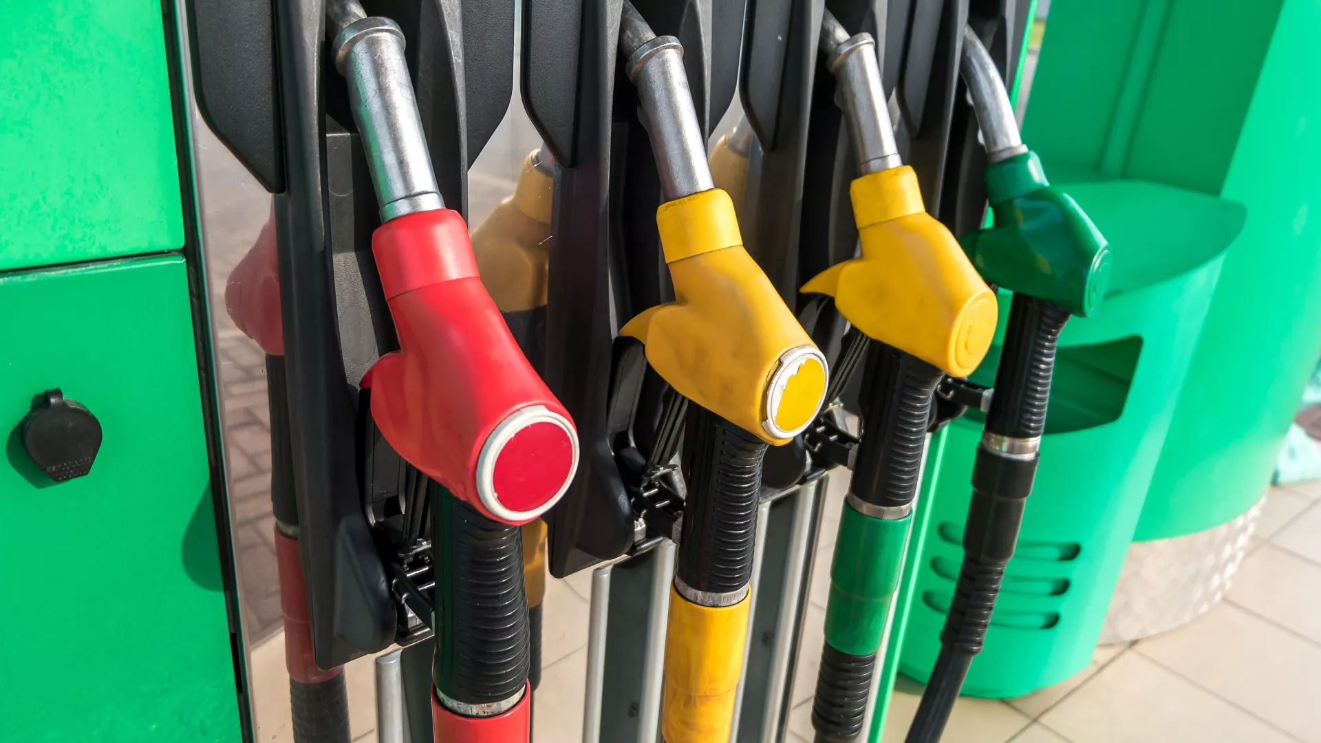 A row of brightly colored gasoline pump nozzles inserted into a gas pump