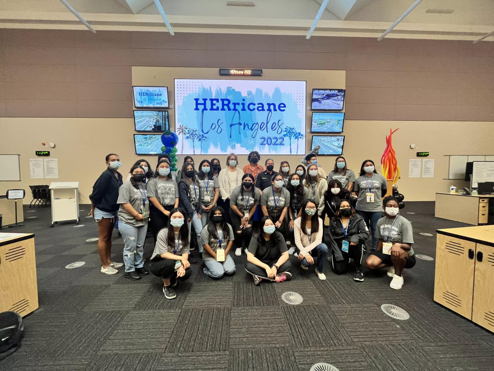 HERricane Program attendees take a picture in front of a screen with HERricane Los Angeles 2022 as the background.