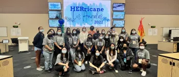 HERricane Program attendees take a picture in front of a screen with HERricane Los Angeles 2022 as the background.