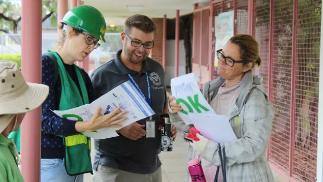 Three people review a plan during an earthquake drill 