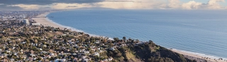 Photo of the coastline of Pacific Palisades before the 2025 wildfires, with rows of homes in the foreground.