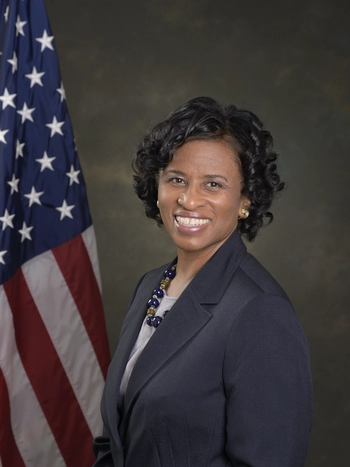 Photo of EMD GM Carol Parks standing beside an American flag.