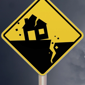 An image of a road signs showing fractured earth from a quake and a crrumbling house above it.