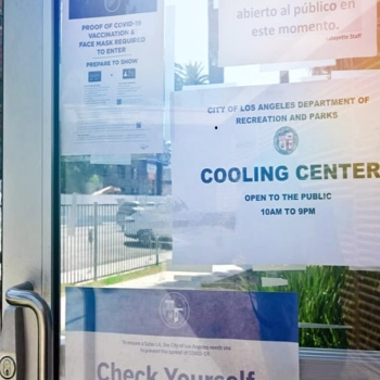 An open door to a City recreation center shows the sign: Cooling Center Open